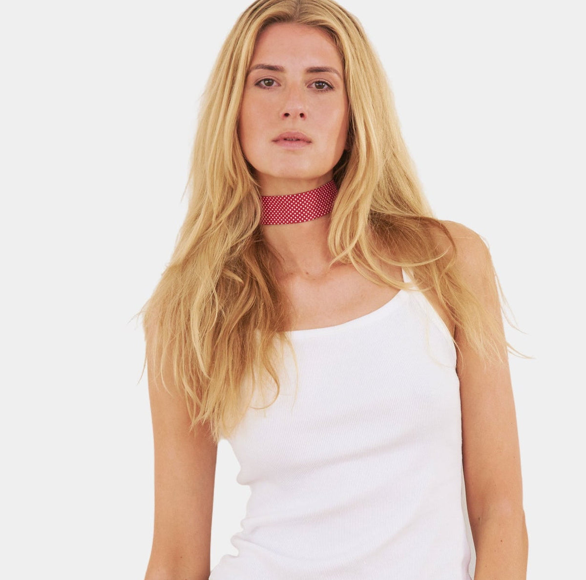 model wearing a bright red silk choker with a repeating white dot pattern