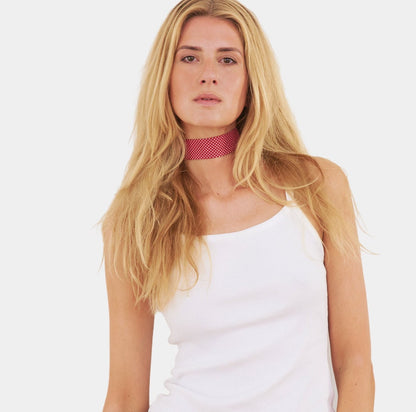 model wearing a bright red silk choker with a repeating white dot pattern