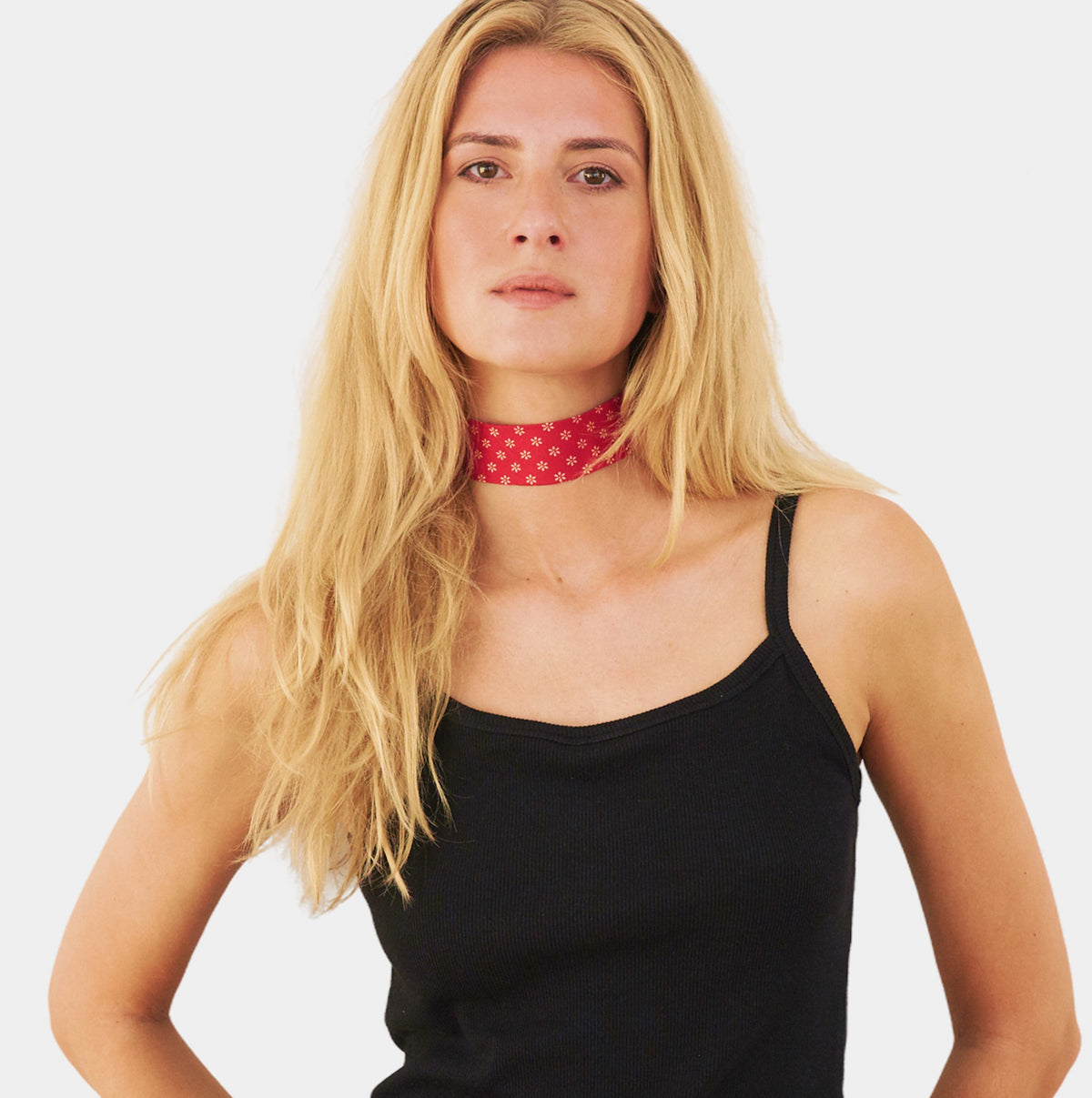 model wearing a red silk choker with a repeating white floral pattern