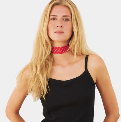 model wearing a red silk choker with a repeating white floral pattern